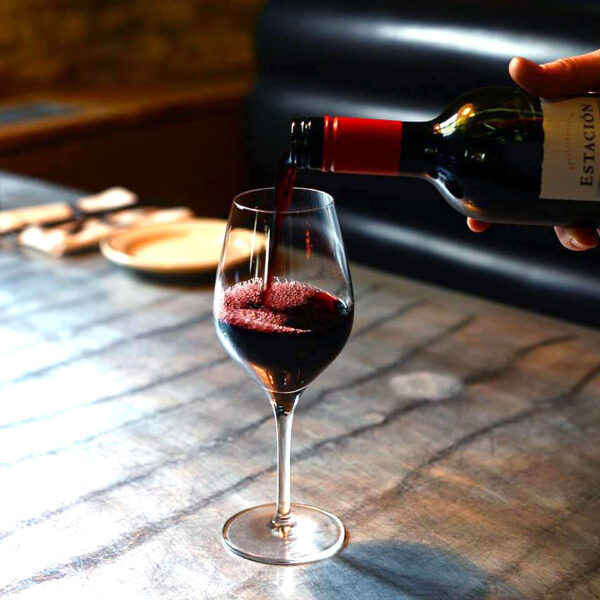 Pouring red wine into a glass on a metal tabletop at a booth