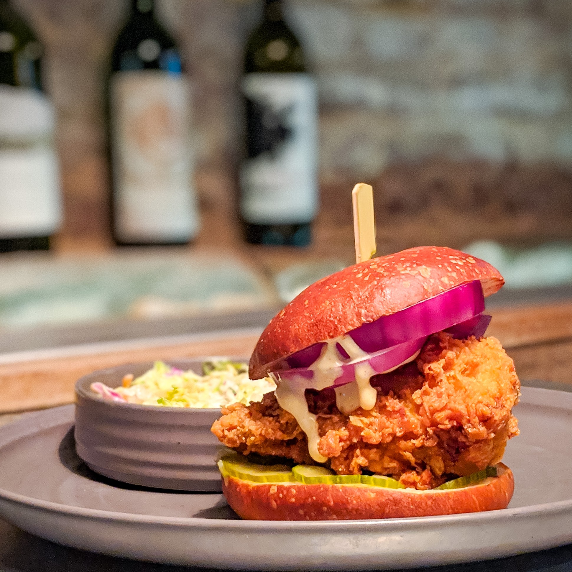 Fried chicken, red onion and pickles on a bun with a side of coleslaw