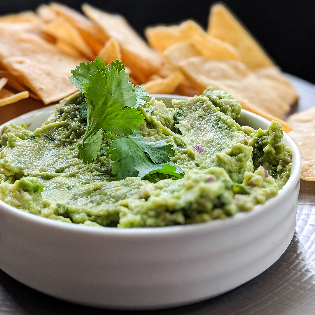 Fresh guacamole garnished with cilantro with tortilla chips