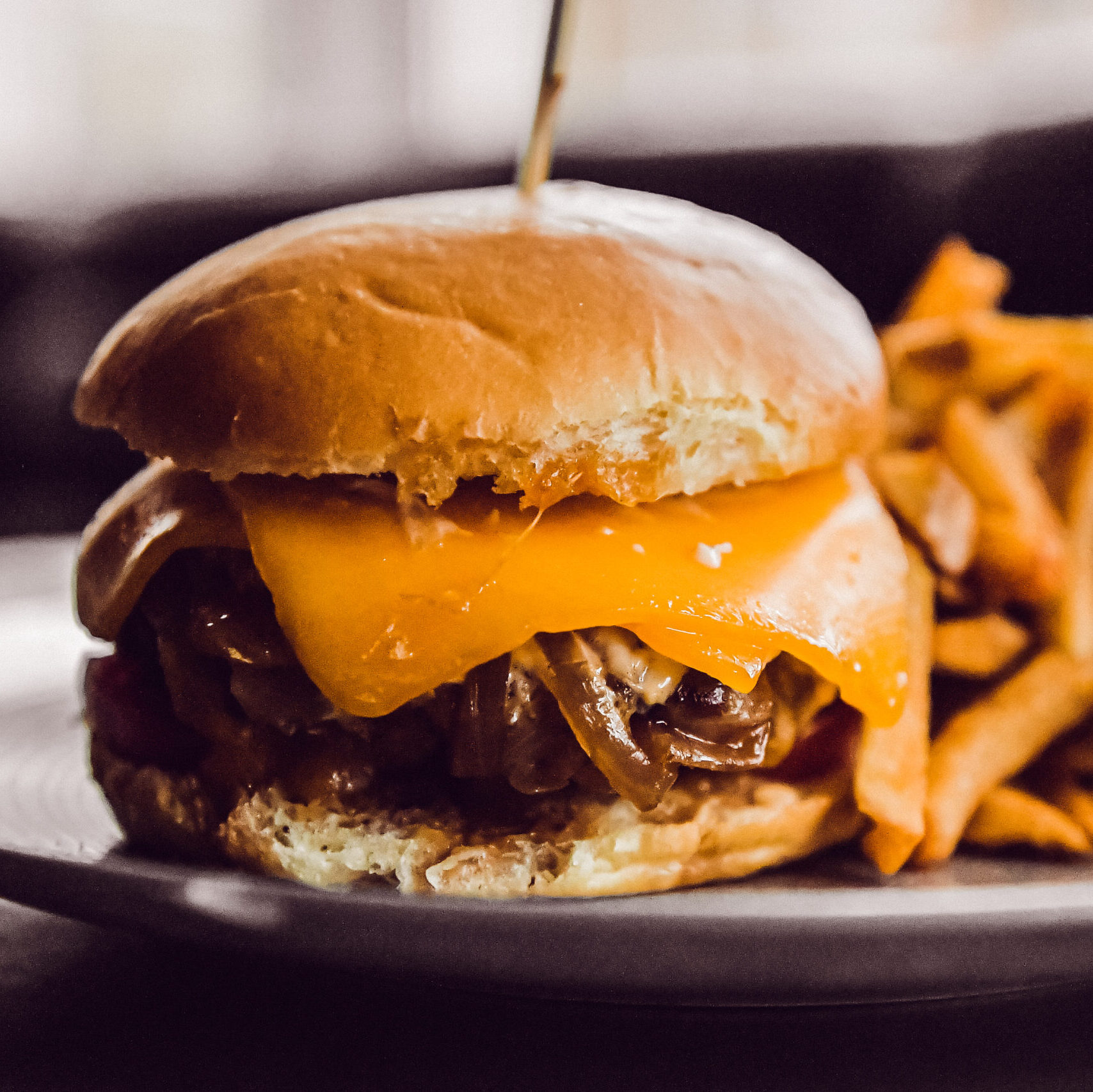 Burger with bacon, cheese and lettuce on plate with fries