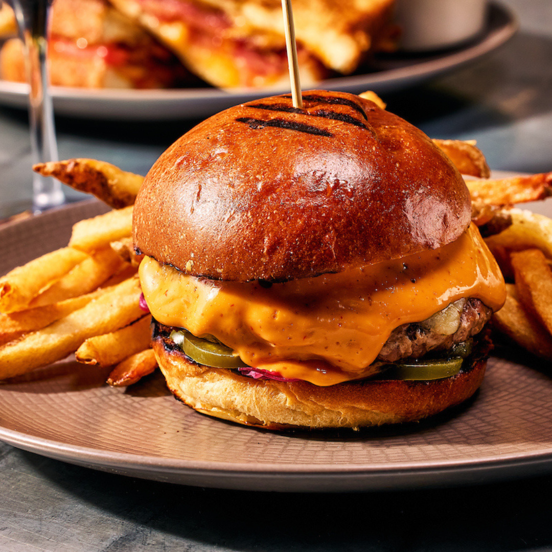 Burger with bacon, cheese and lettuce on plate with fries